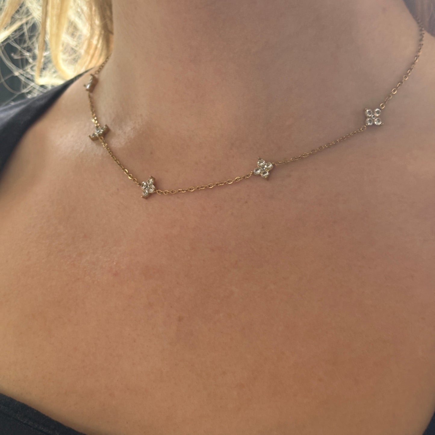 Close-up of a delicate gold necklace with small stones on a person's neck.