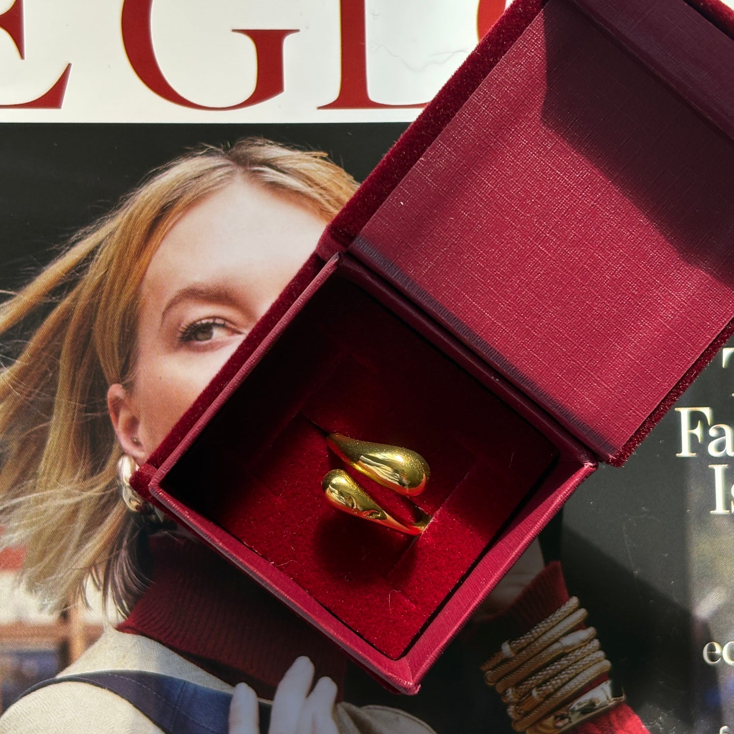 Gold ring in a red box with a magazine in the background