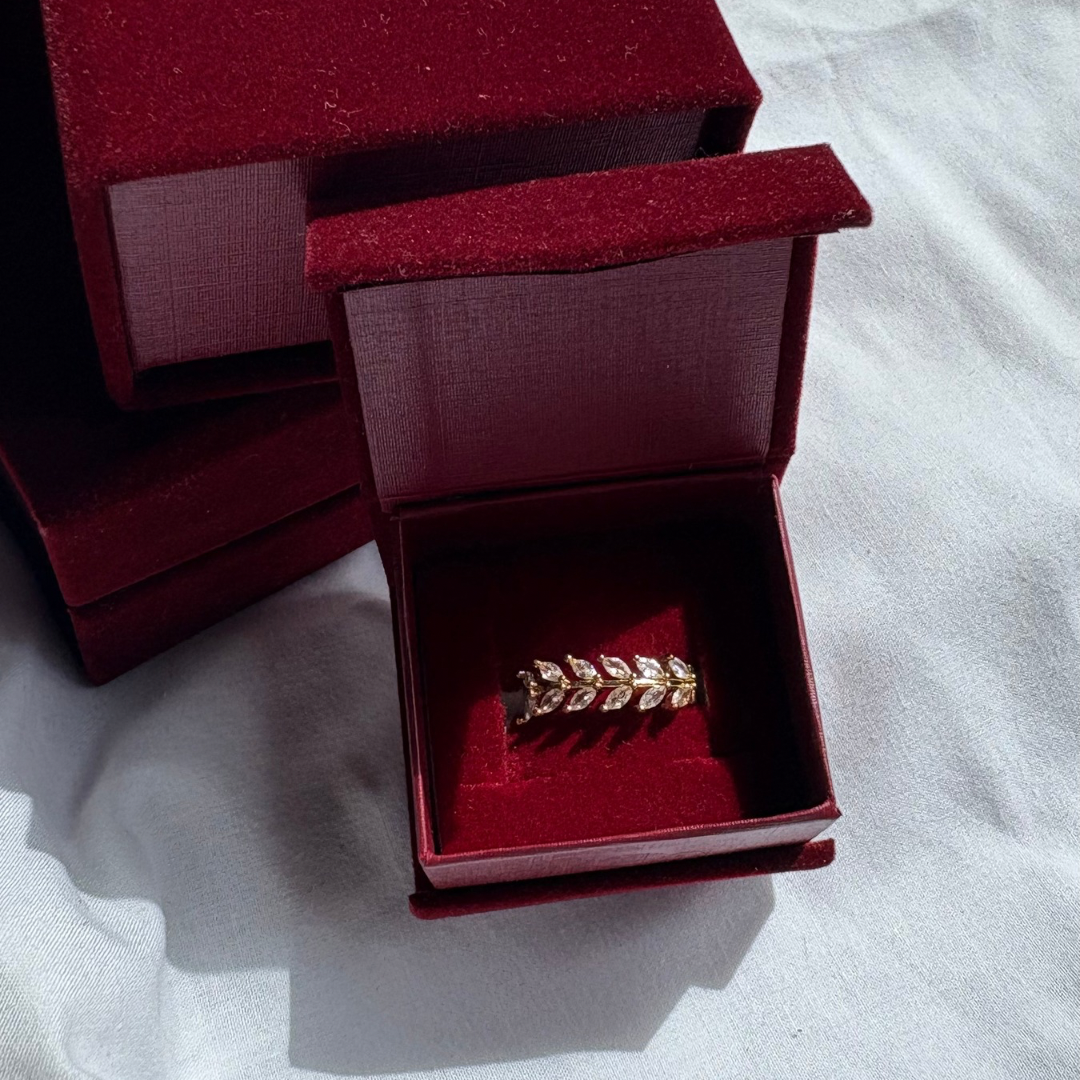 Red jewelry box with a gold ring inside on a white fabric background