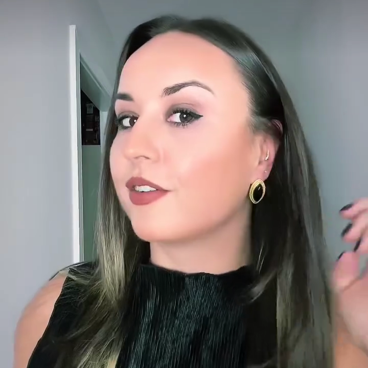 Woman with long hair and earrings taking a mirror selfie.