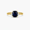 Gold ring with a blue gemstone and smaller diamonds on a white background

