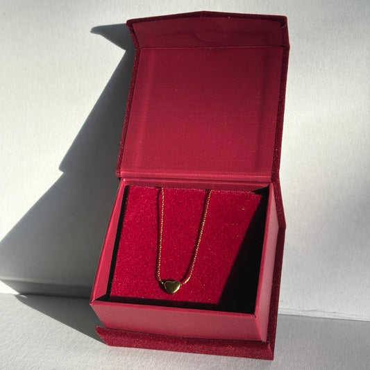 Red jewelry box with a gold ring inside on a light gray background

