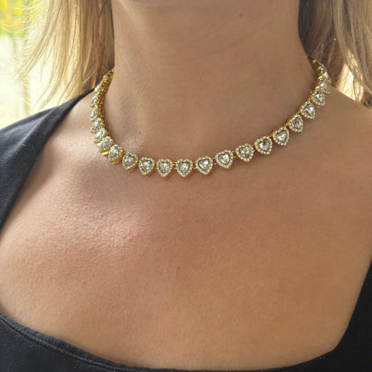 Gold necklace with heart-shaped diamonds on a person wearing a black top.

