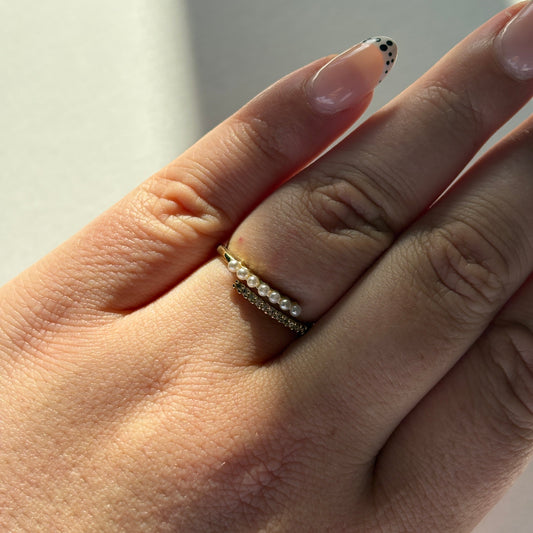 Close-up of a hand wearing a gold ring with a blurred background

