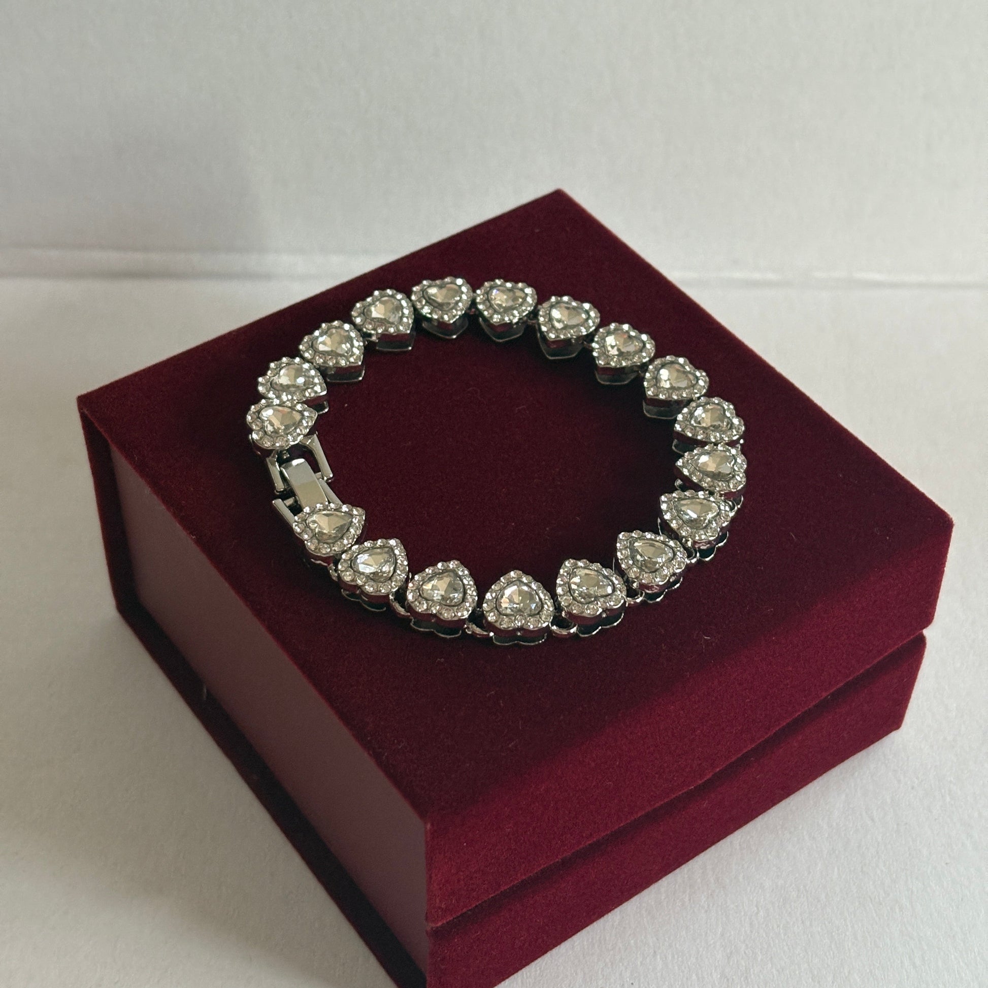 Silver bracelet with heart-shaped stones on a red box against a white background

