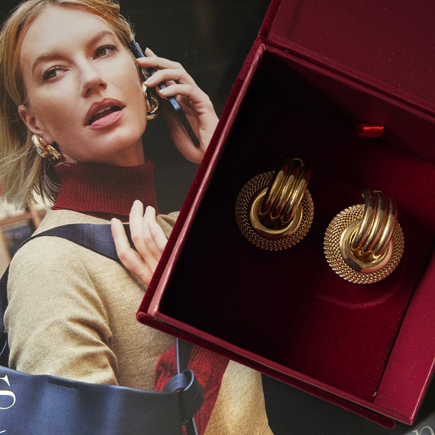 Gold earrings in a red box with a magazine underneath