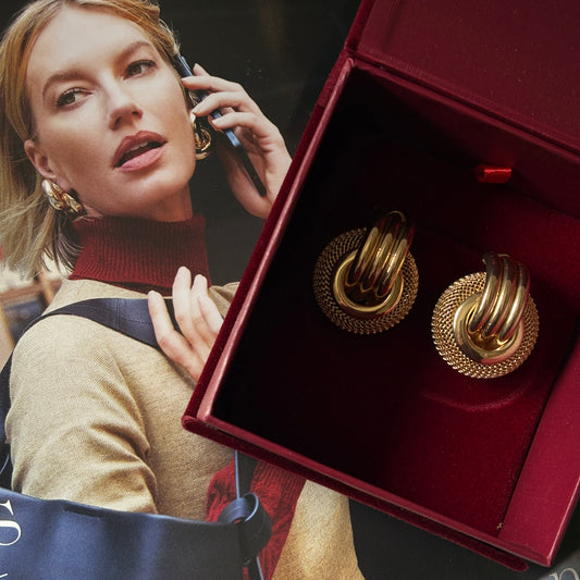 Gold earrings in a red box with a magazine underneath