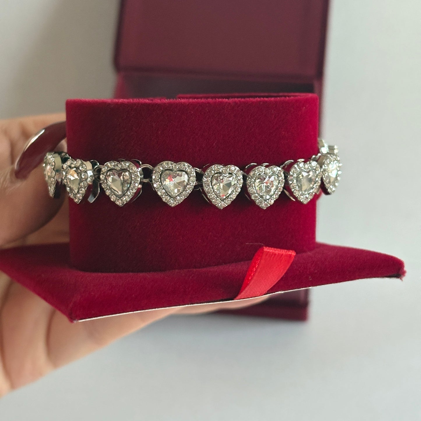 Diamond bracelet held over a red jewelry box

