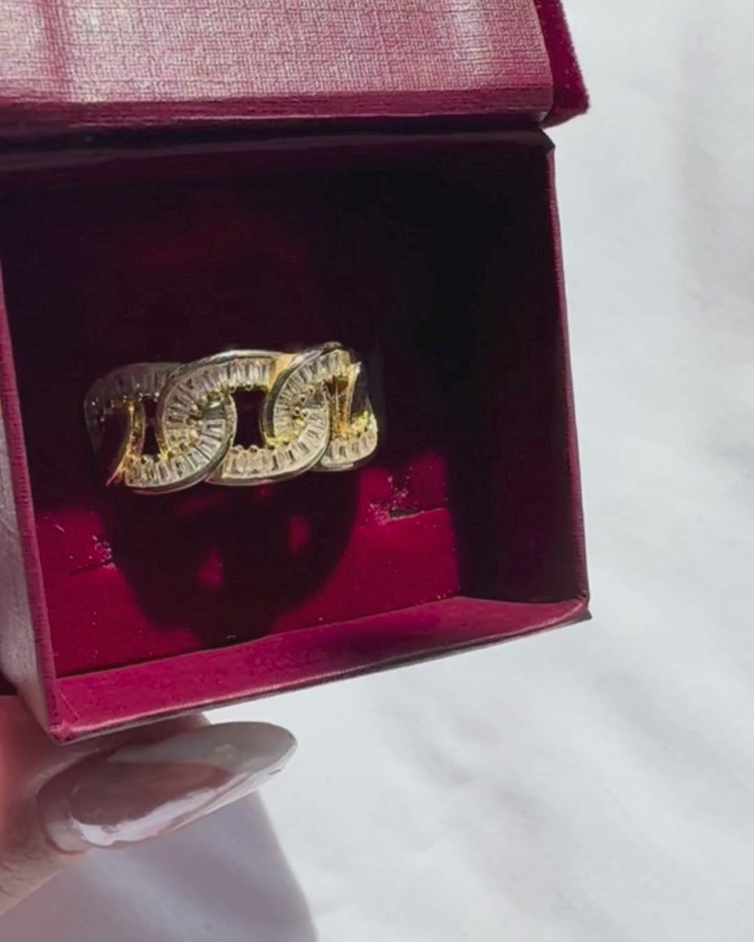 Gold ring with red gemstones in a red jewellery box on a white surface

